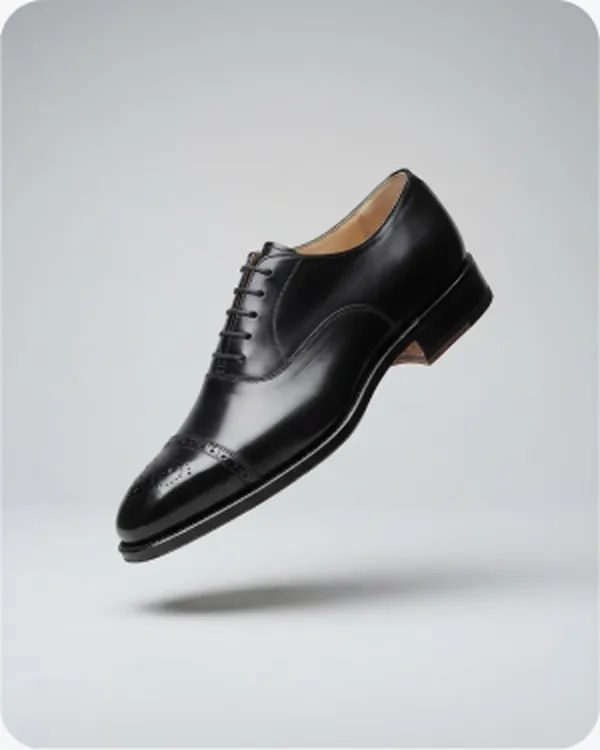 Black oxford shoe floating on a plain ground